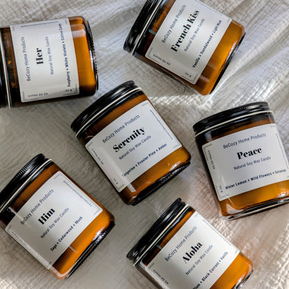 Collection of BeCozy soy wax candle jars with labels on a textured surface