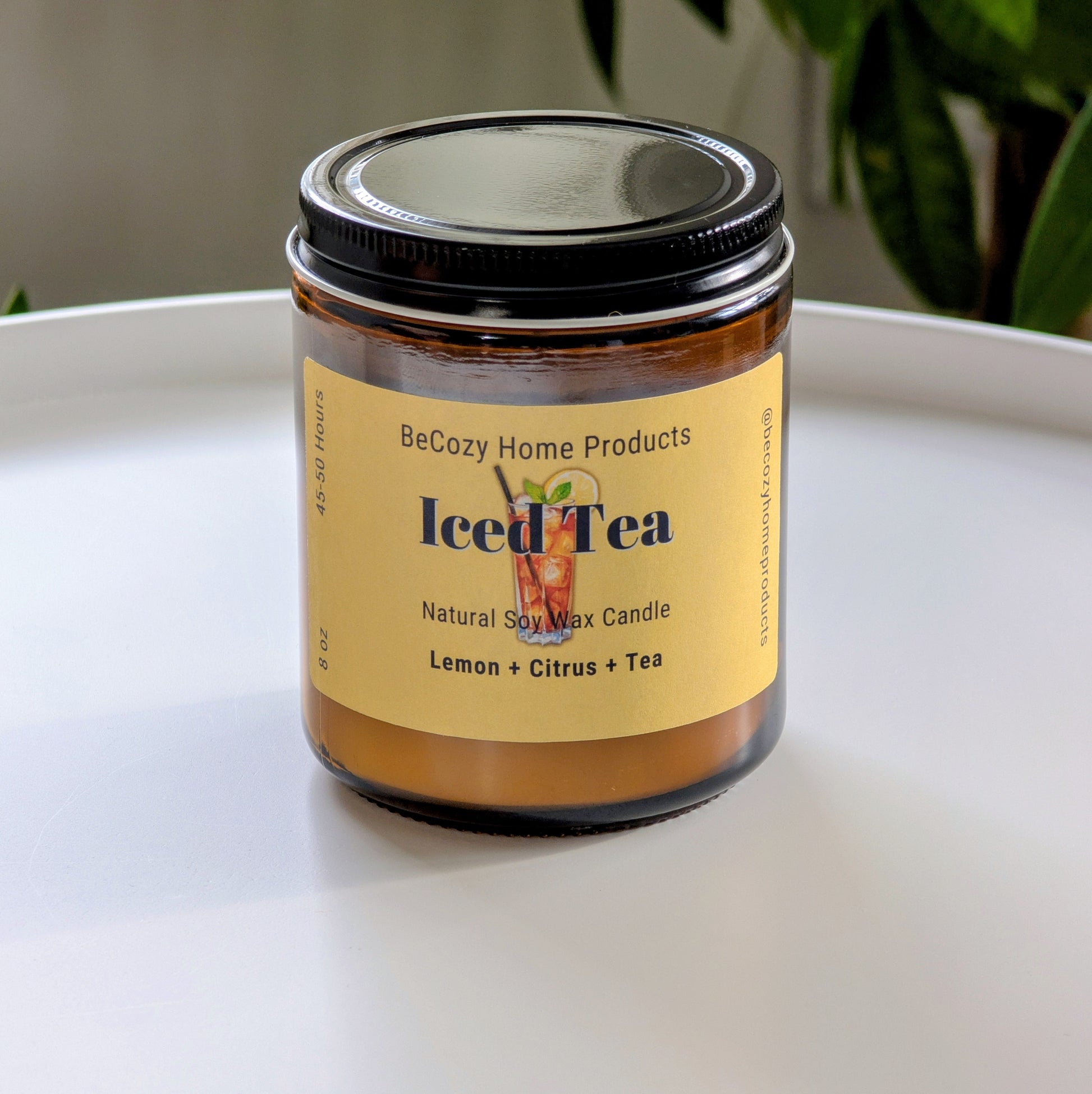 BeCozy Home Products iced tea soy wax candle on a white surface with a plant in the background