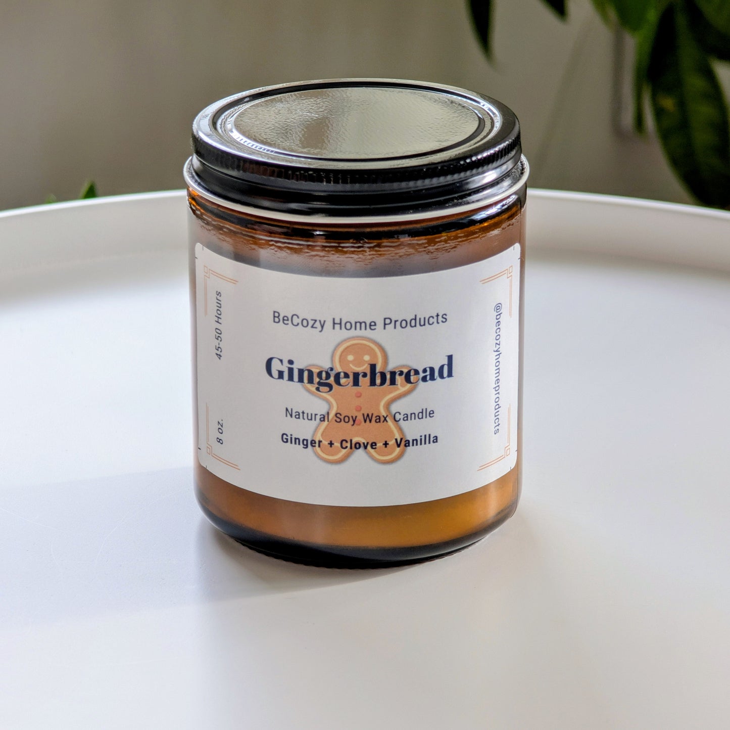 Gingerbread soy wax candle in a glass jar with a label on a white surface.