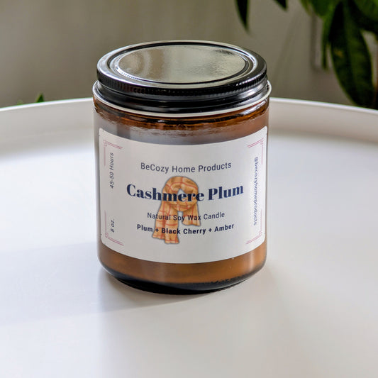 BeCozy Home Products Cashmere Plum soy wax candle on a white surface with a neutral background